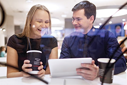 Woman laughs as man shows tablet